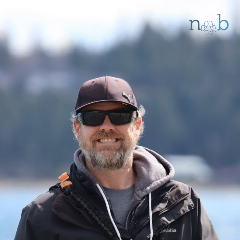 Peter smiling at the beach with hat and sunglasses on