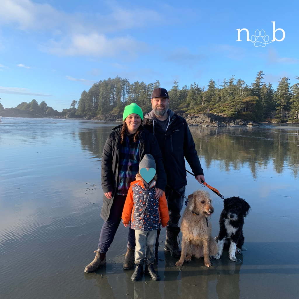 family on the beach at cox bay with two dogs